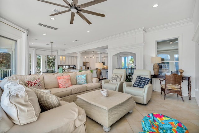 tiled living room with crown molding, ceiling fan, and decorative columns