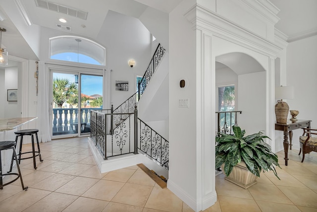 foyer featuring a high ceiling, light tile patterned flooring, and crown molding