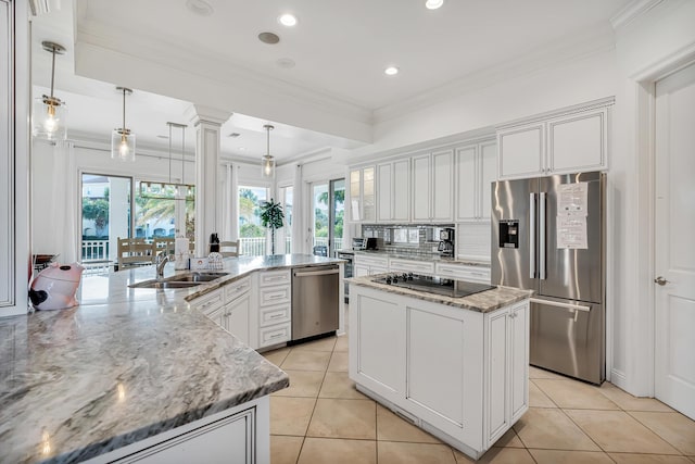 kitchen featuring light stone countertops, decorative light fixtures, stainless steel appliances, and a center island with sink