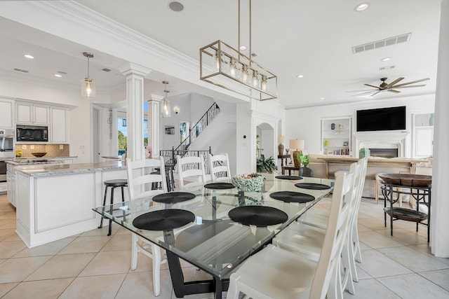 dining room with light tile patterned floors, crown molding, decorative columns, and ceiling fan