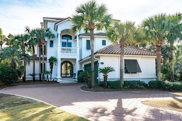 mediterranean / spanish home featuring a garage, french doors, and a balcony