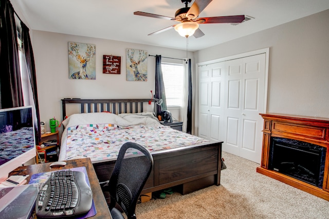 bedroom with a closet, a ceiling fan, a premium fireplace, and carpet flooring