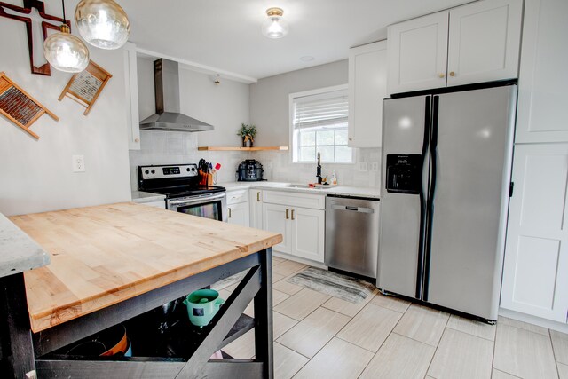 kitchen featuring a sink, stainless steel appliances, light countertops, wall chimney range hood, and tasteful backsplash