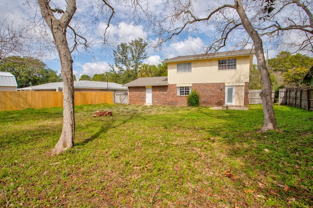 rear view of property featuring a yard, brick siding, and a fenced backyard