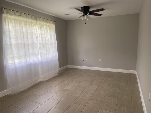 spare room with baseboards, ceiling fan, and wood tiled floor