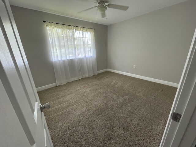 carpeted spare room featuring a ceiling fan and baseboards