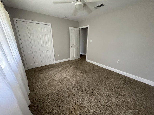 unfurnished bedroom with a ceiling fan, visible vents, baseboards, a closet, and dark colored carpet