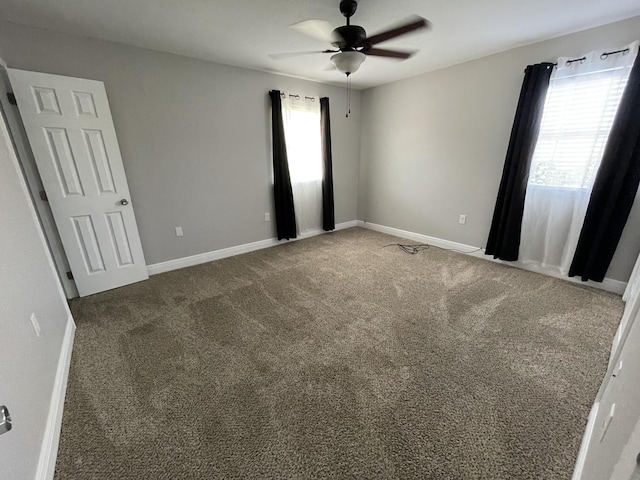 carpeted empty room with ceiling fan and baseboards