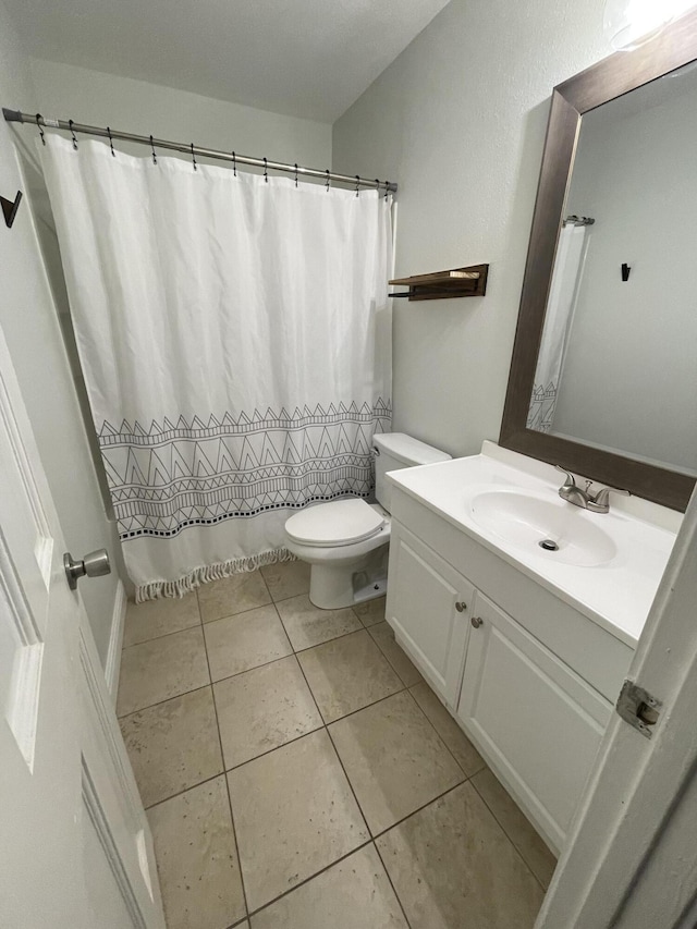 bathroom featuring tile patterned flooring, a shower with shower curtain, toilet, and vanity