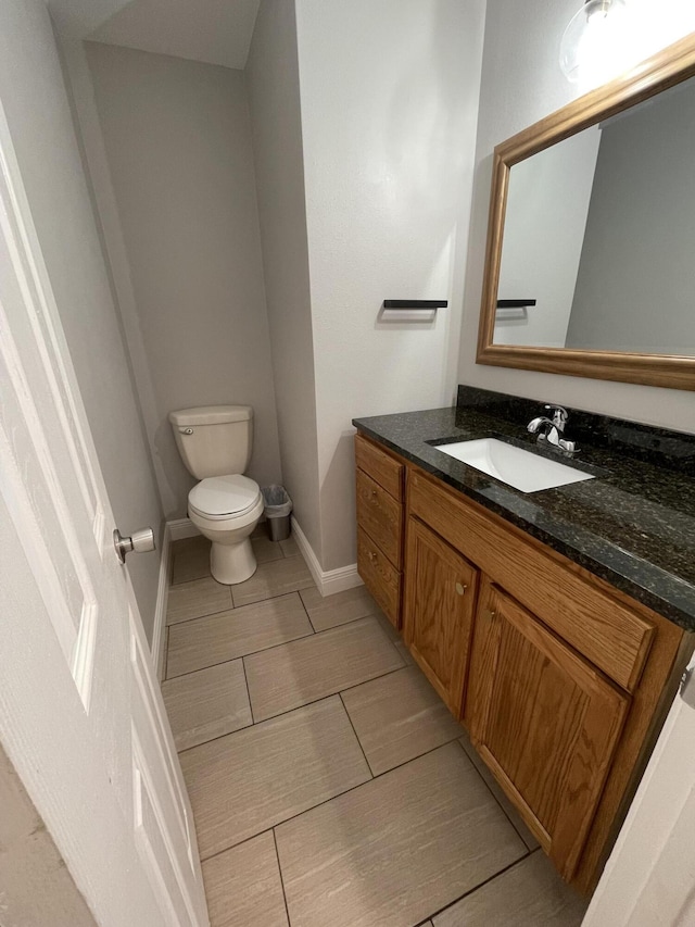 half bath with vanity, toilet, and baseboards