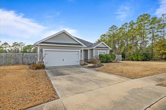 view of front of property with concrete driveway, stone siding, an attached garage, and fence