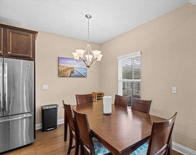 dining room with a notable chandelier, baseboards, and wood finished floors