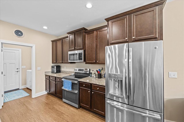 kitchen with appliances with stainless steel finishes, light stone counters, dark brown cabinets, light wood-style floors, and recessed lighting