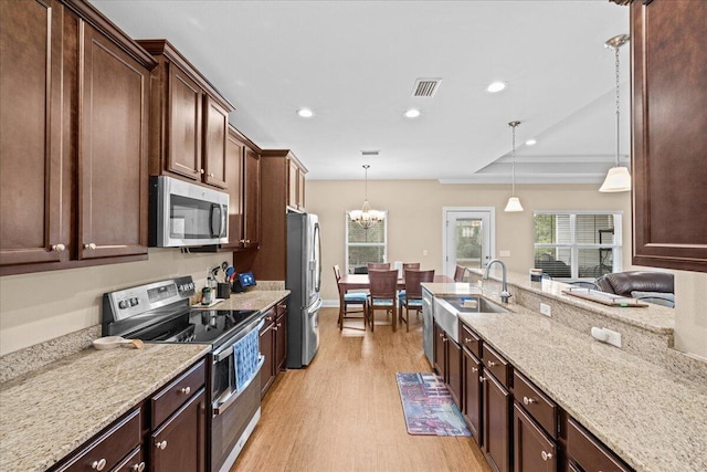 kitchen with light stone counters, recessed lighting, light wood-style flooring, appliances with stainless steel finishes, and a sink