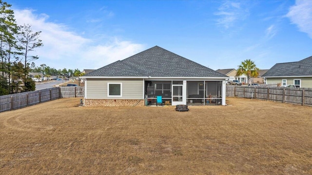 back of property featuring a fenced backyard, brick siding, a sunroom, a yard, and roof with shingles