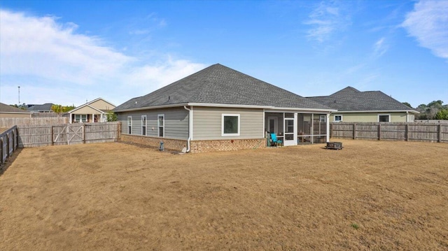 back of house featuring brick siding, a lawn, a fenced backyard, and a sunroom