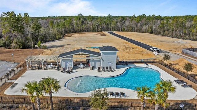 community pool with a wooded view, fence, a pergola, and a patio