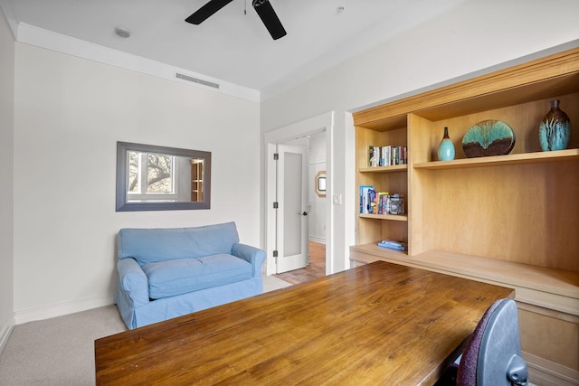 carpeted office space featuring crown molding and ceiling fan
