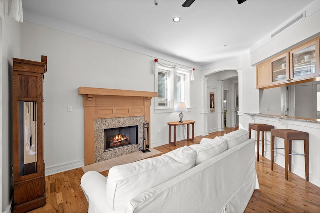 living room featuring crown molding, decorative columns, ceiling fan, and light wood-type flooring
