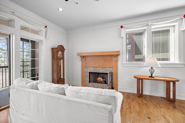 living room with ornamental molding, a high end fireplace, and light hardwood / wood-style flooring
