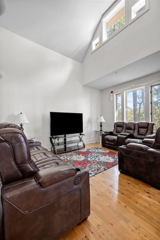 living room with a healthy amount of sunlight, high vaulted ceiling, and light hardwood / wood-style flooring