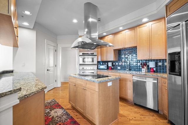 kitchen with appliances with stainless steel finishes, a center island, light stone countertops, and island range hood