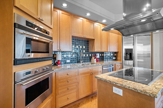 kitchen with sink, stainless steel appliances, island exhaust hood, light stone countertops, and a kitchen island