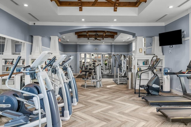 workout area featuring ceiling fan, a raised ceiling, decorative columns, and light parquet floors