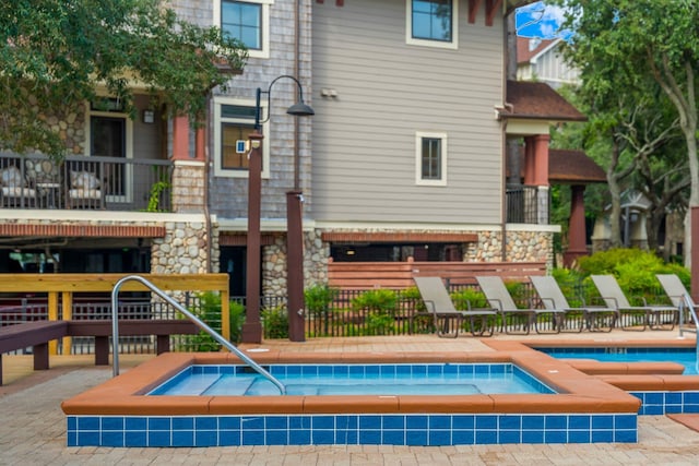 back of property featuring a swimming pool with hot tub