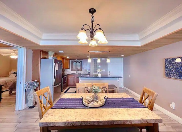 dining area with crown molding, sink, ceiling fan with notable chandelier, and a tray ceiling