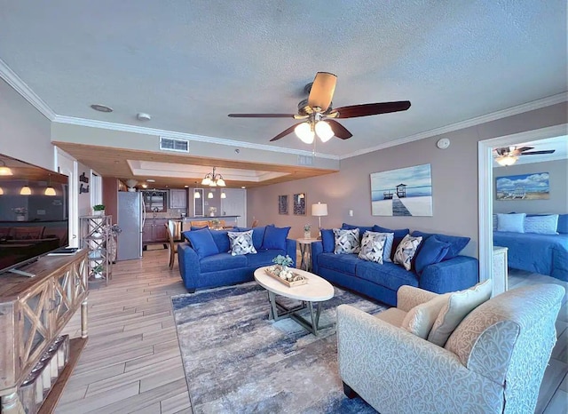 living room with ceiling fan, crown molding, a textured ceiling, and light wood-type flooring