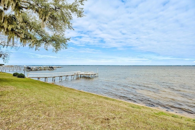 view of dock with a yard and a water view