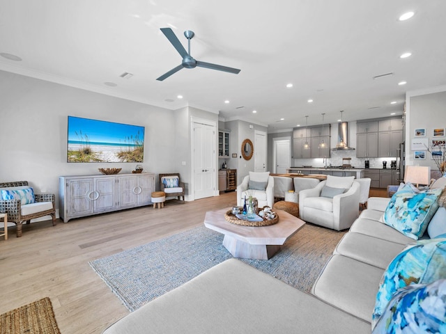 living room featuring crown molding, ceiling fan, sink, and light hardwood / wood-style floors