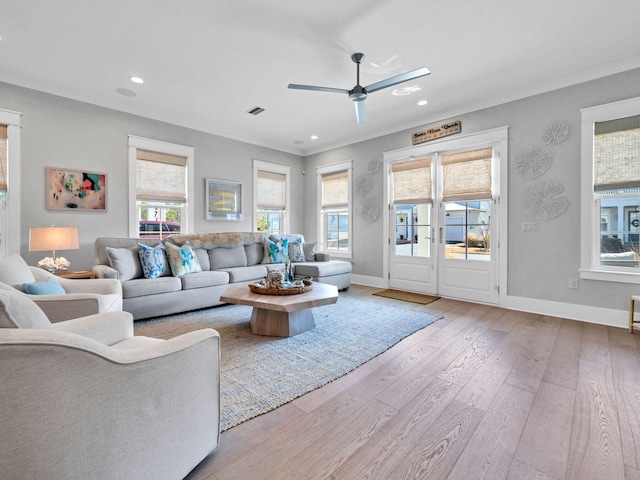 living room with ornamental molding, ceiling fan, and light wood-type flooring