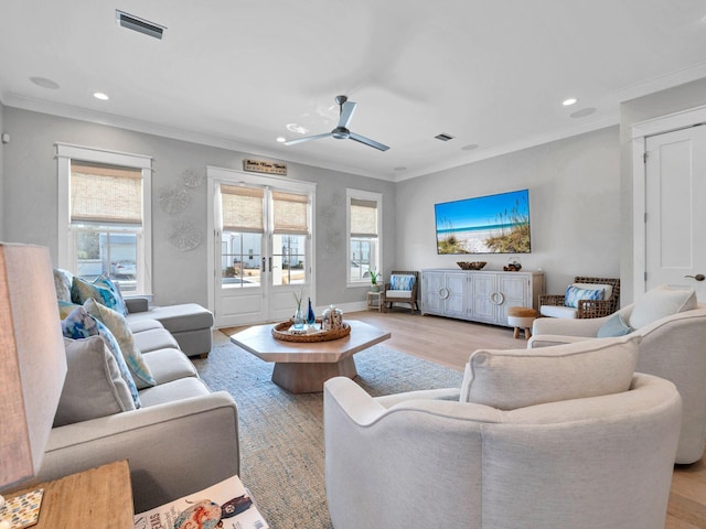 living room featuring light hardwood / wood-style flooring, ornamental molding, and a healthy amount of sunlight