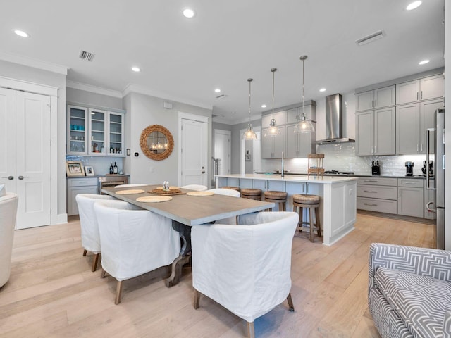 dining room with sink, light hardwood / wood-style flooring, and ornamental molding