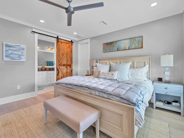 bedroom featuring crown molding, ensuite bath, light wood-type flooring, ceiling fan, and a barn door