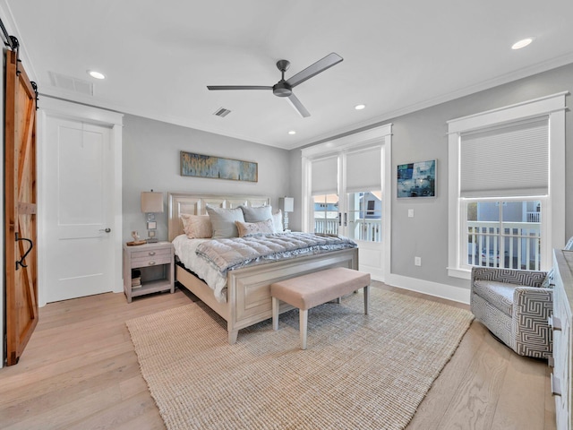 bedroom featuring ceiling fan, ornamental molding, a barn door, and light wood-type flooring