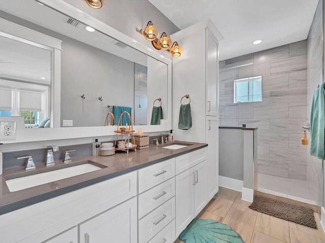 bathroom featuring tiled shower and vanity