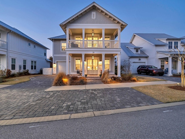 view of front facade with a garage, a balcony, and a porch