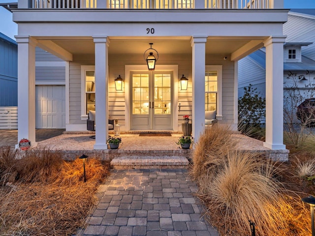 doorway to property with french doors, a garage, and covered porch