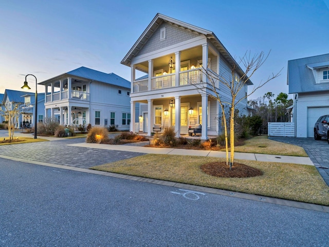 view of front of home with a balcony, covered porch, and a lawn