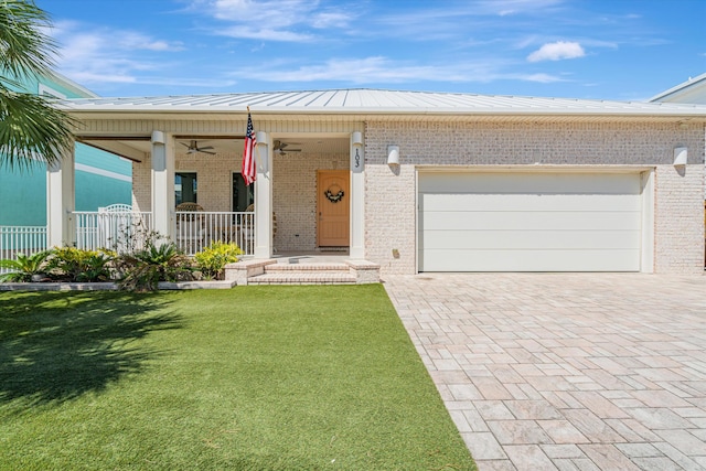 view of front of house with a garage, a front lawn, ceiling fan, and covered porch