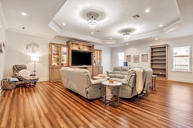 living room featuring crown molding, hardwood / wood-style floors, and a tray ceiling