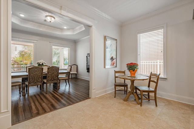 dining area with ornamental molding, light tile patterned floors, and a tray ceiling