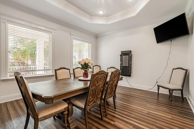 dining space featuring a raised ceiling, ornamental molding, and dark hardwood / wood-style flooring