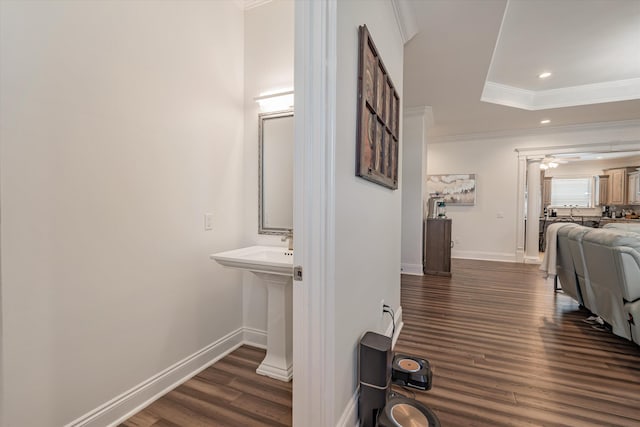 corridor featuring dark hardwood / wood-style flooring, crown molding, and a tray ceiling