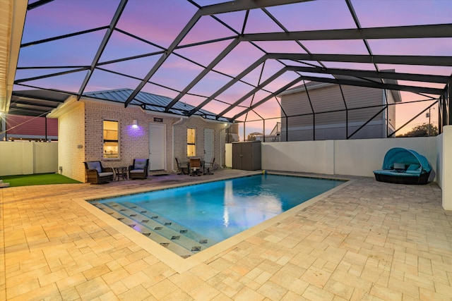 pool at dusk with a patio area and glass enclosure