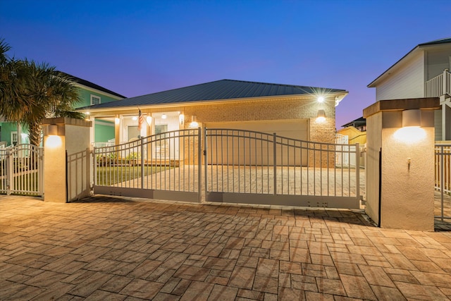 gate at dusk featuring a garage