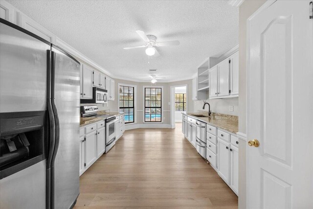 2185 Calle De Castelar, Navarre, FL 32566 - kitchen with sink, light stone counters, light hardwood / wood-style flooring, appliances with stainless steel finishes, and white cabinets